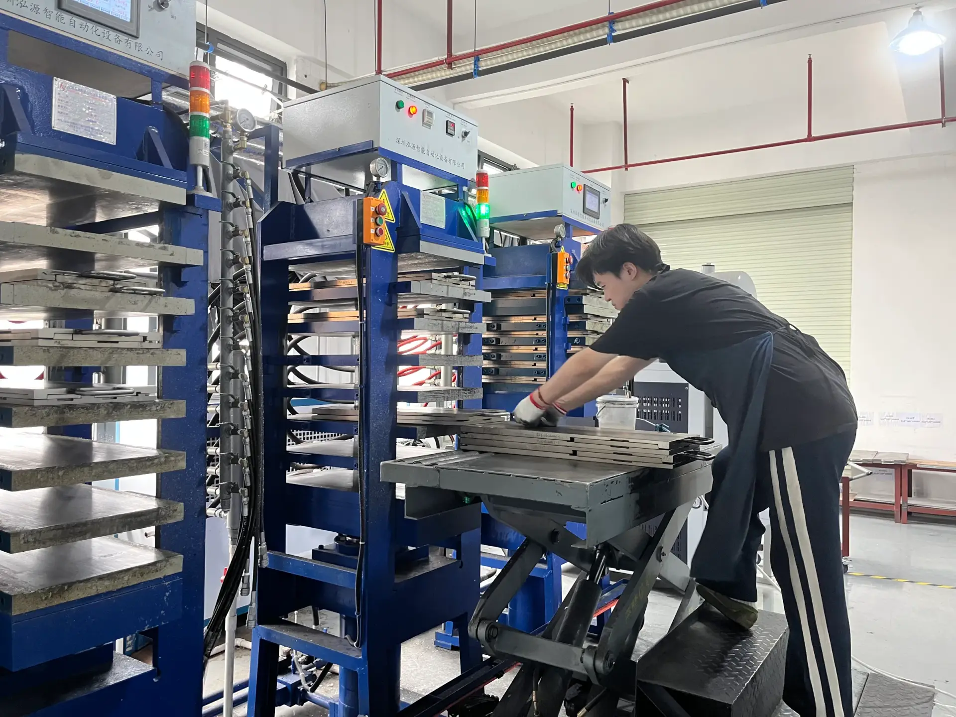 Operator working at multi-layer hot press equipment in SHUEN’s Dongguan factory.