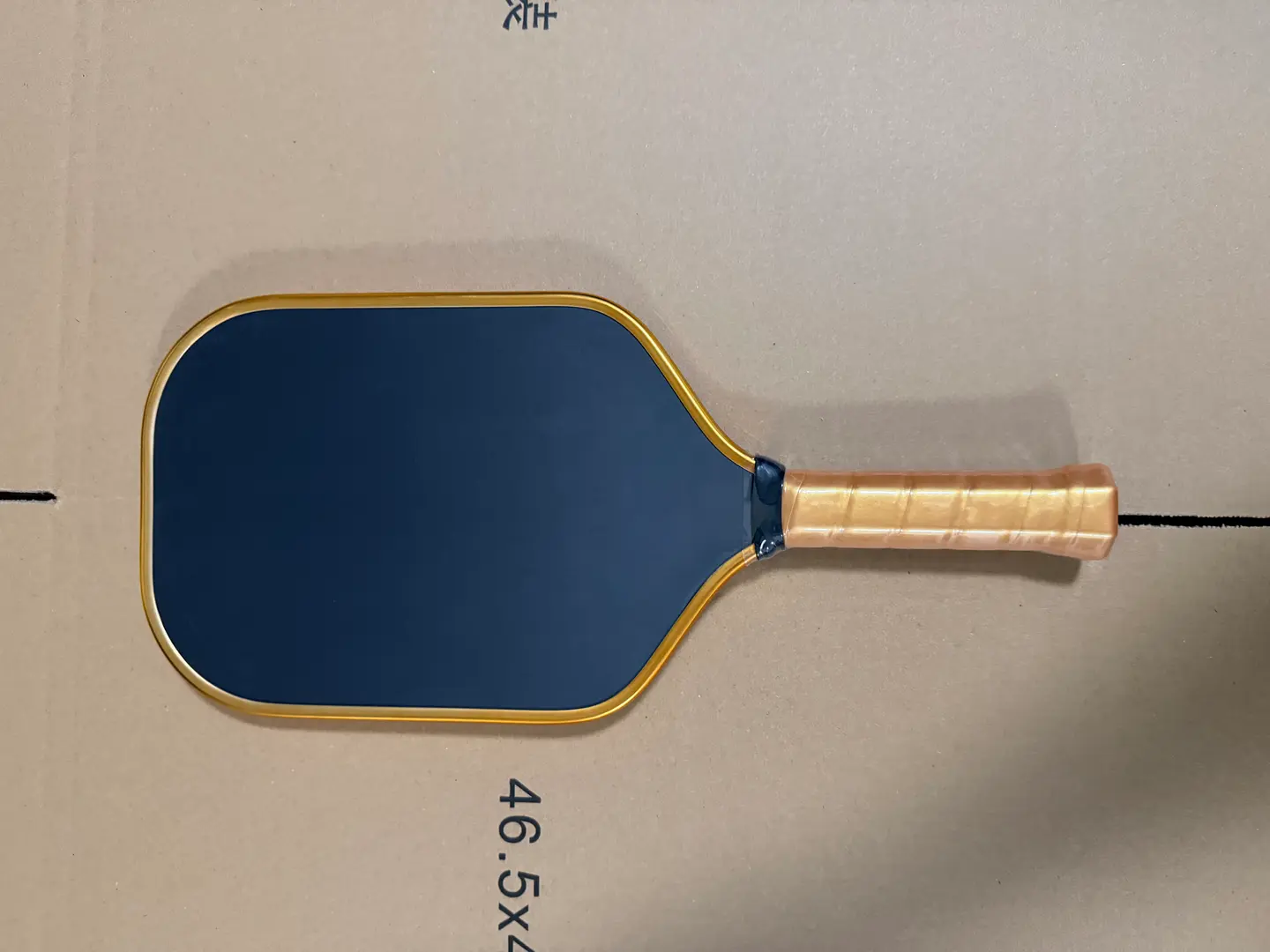 Front view of the finished dark paddle with a gold-colored edge and wrapped handle
