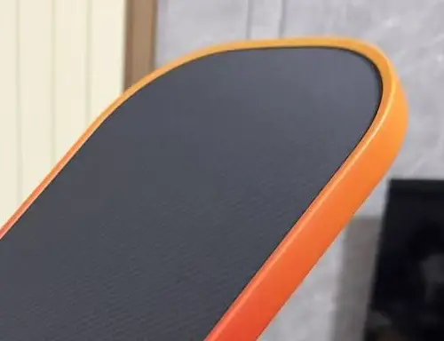 Project close-up of a dark textured paddle face meeting an orange gradient edge