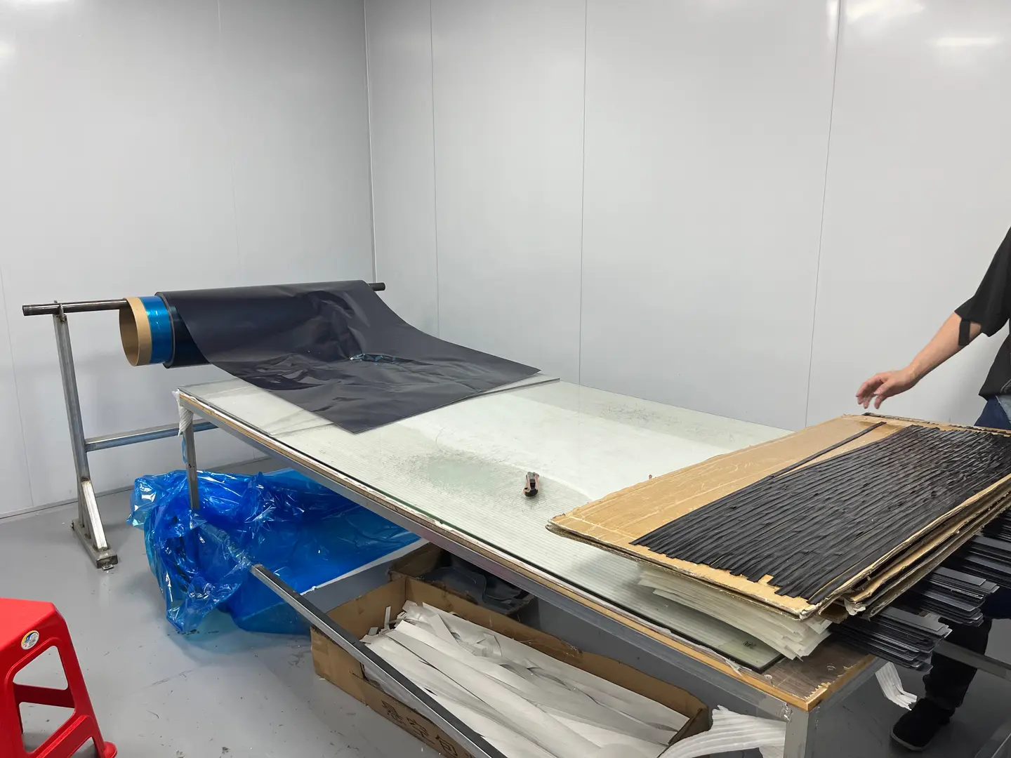 Factory material preparation table with dark sheet material laid out beside cutting work