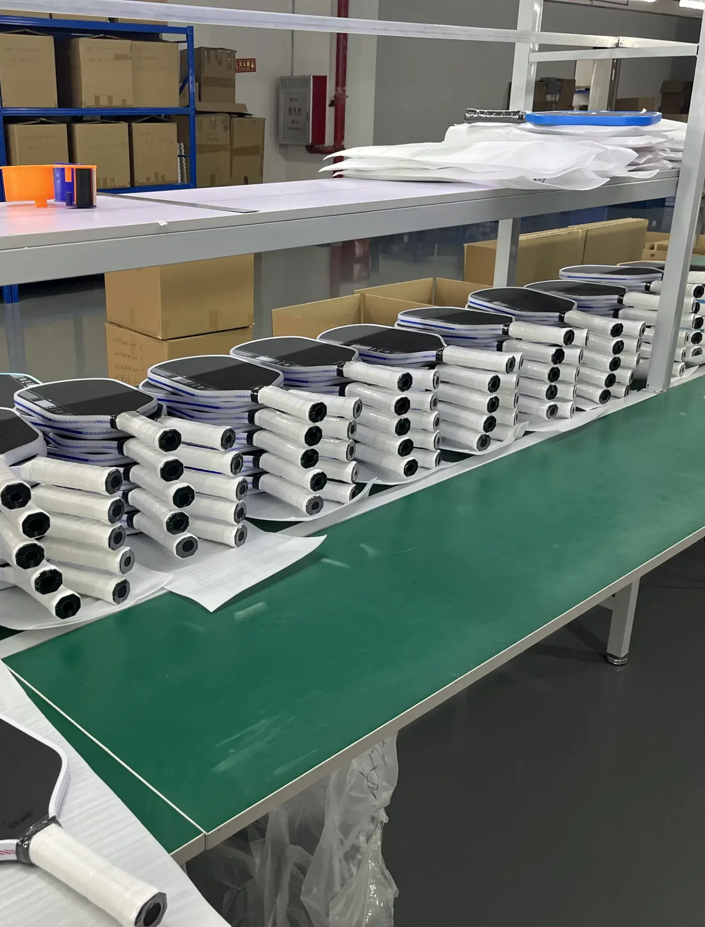 Genuine factory photograph showing rows of finished paddles on a production worktable