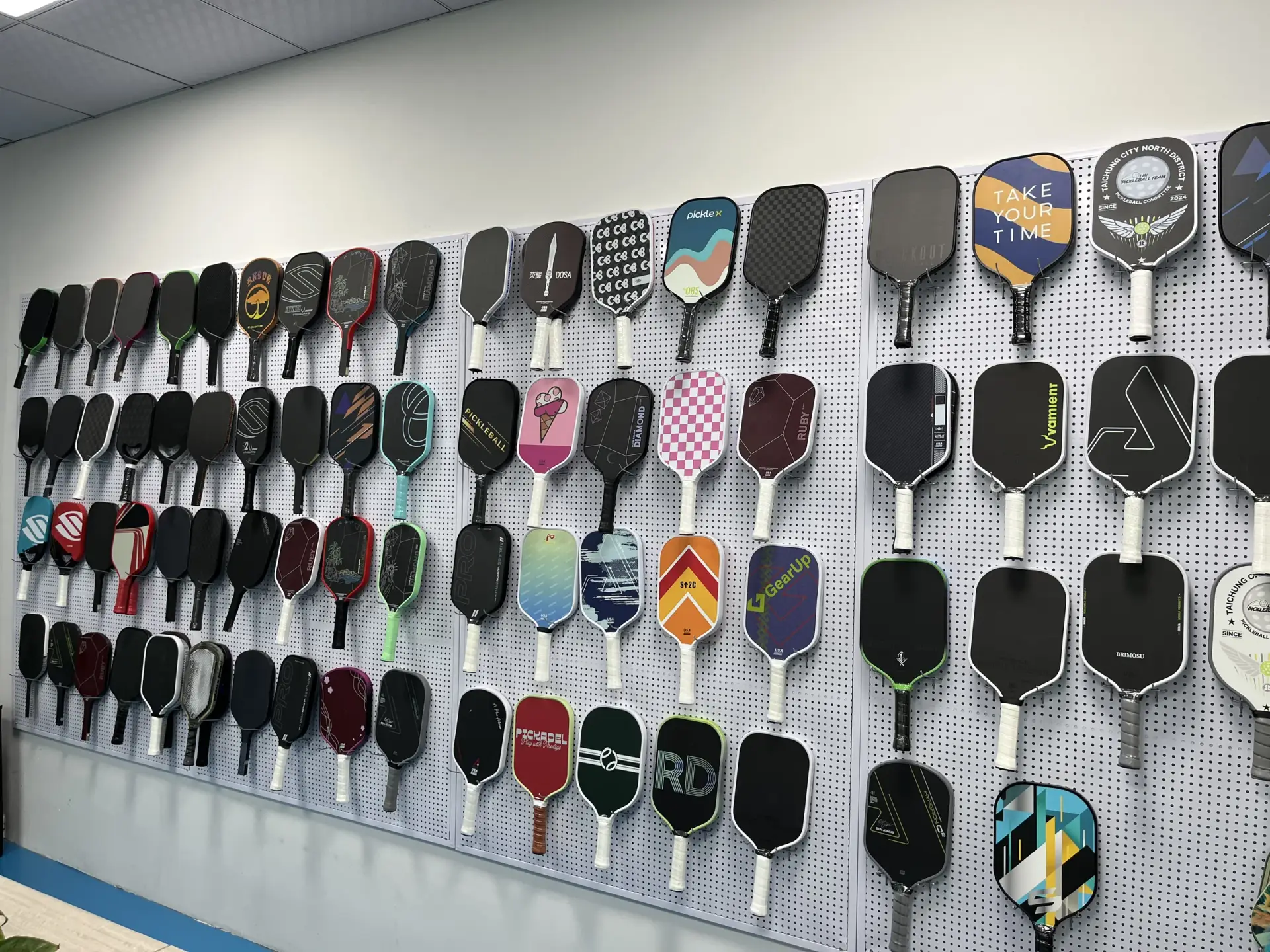 Rows of pickleball paddles mounted on a showroom display wall