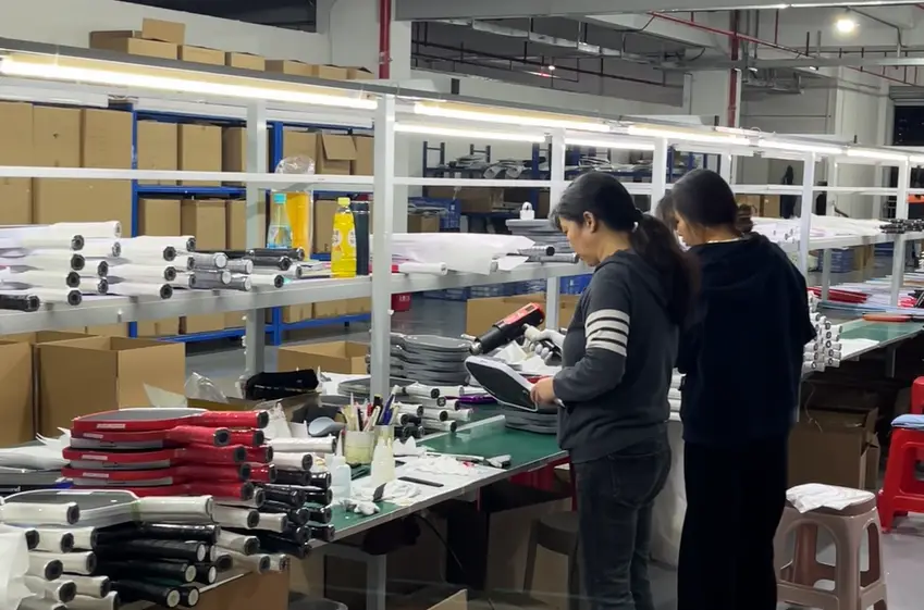 Two workers handling paddles at a factory worktable